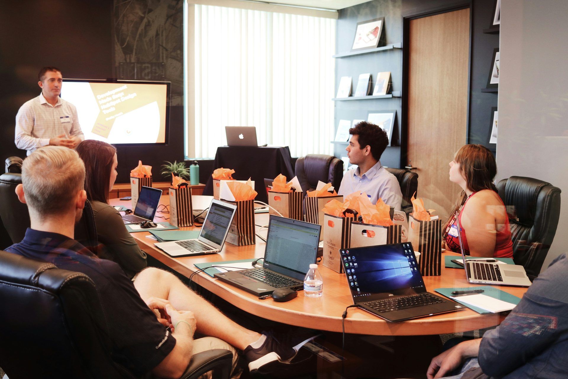 Deelnemers doen mee aan een zakelijke workshop in een moderne conferentieruimte met laptops en cadeautassen.