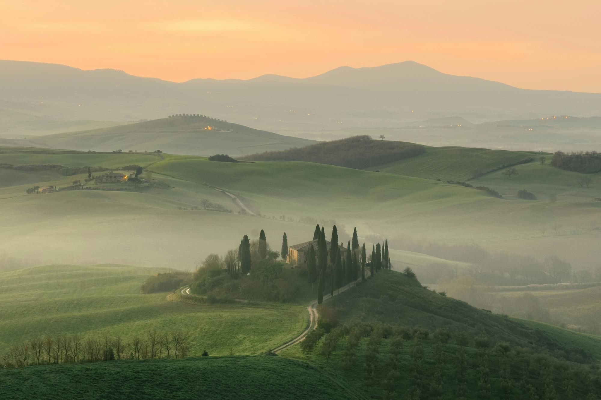 Historic Tuscan villa on a misty hilltop surrounded by cypress trees