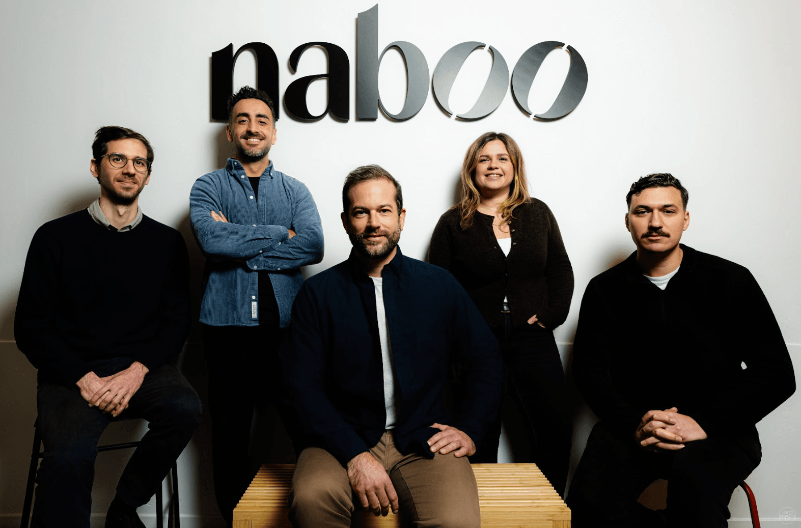 Naboo team members standing in front of the Naboo logo