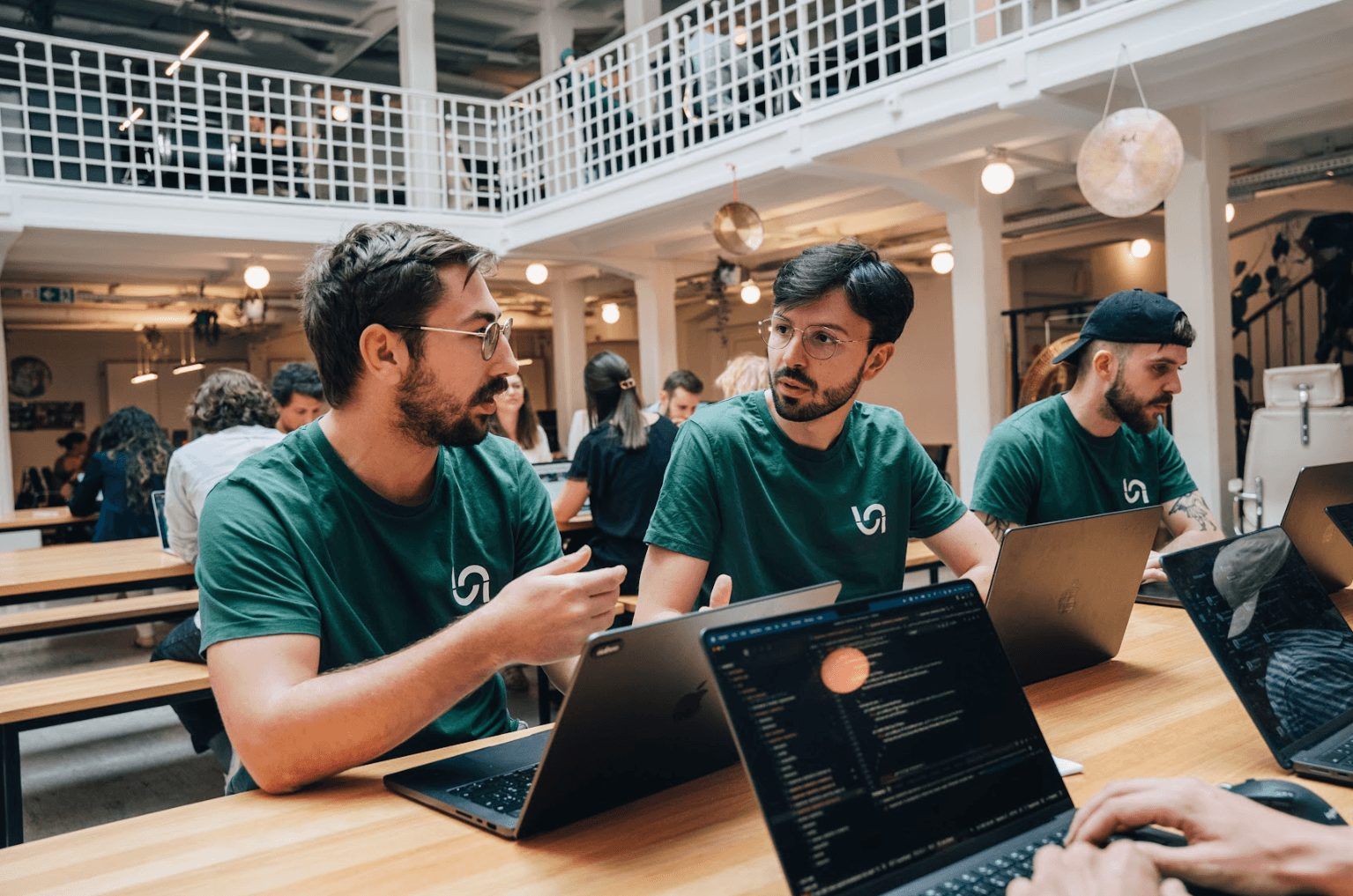 Naboo team members in green Naboo T-shirts working together on laptops in the office