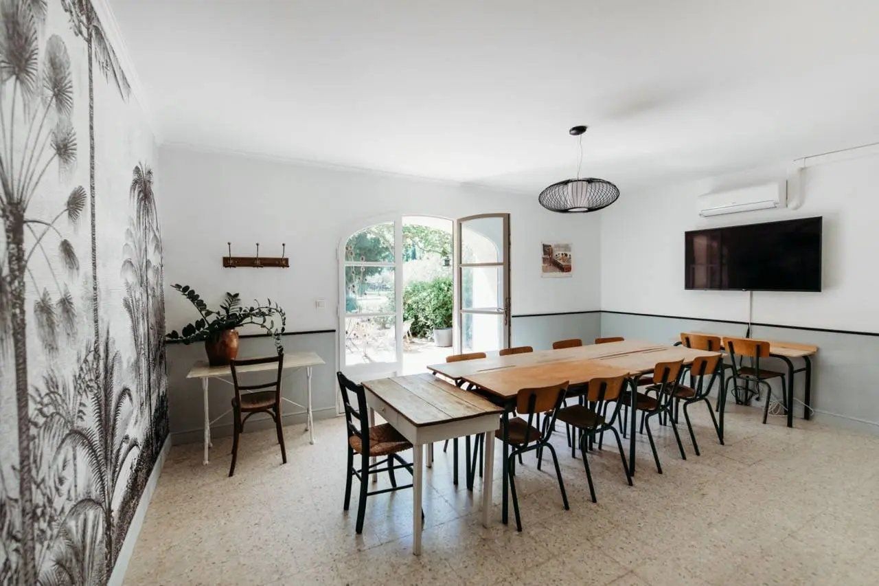 Ruime locatie voor bedrijfsevenementen met lange tafel, stoelen, tv en toegang tot de tuin.
