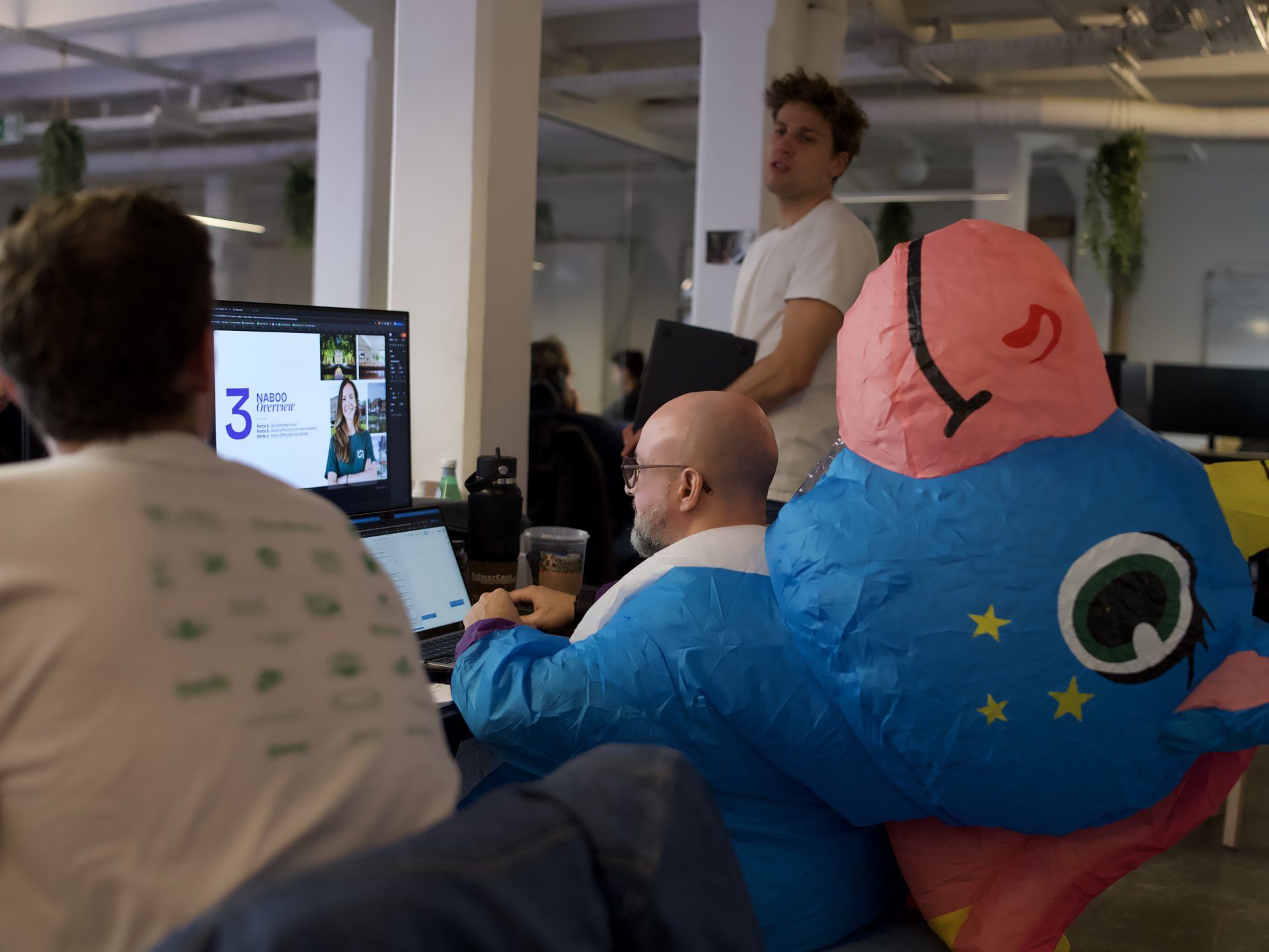 A developer in an inflatable costume working next to colleagues during the hackathon