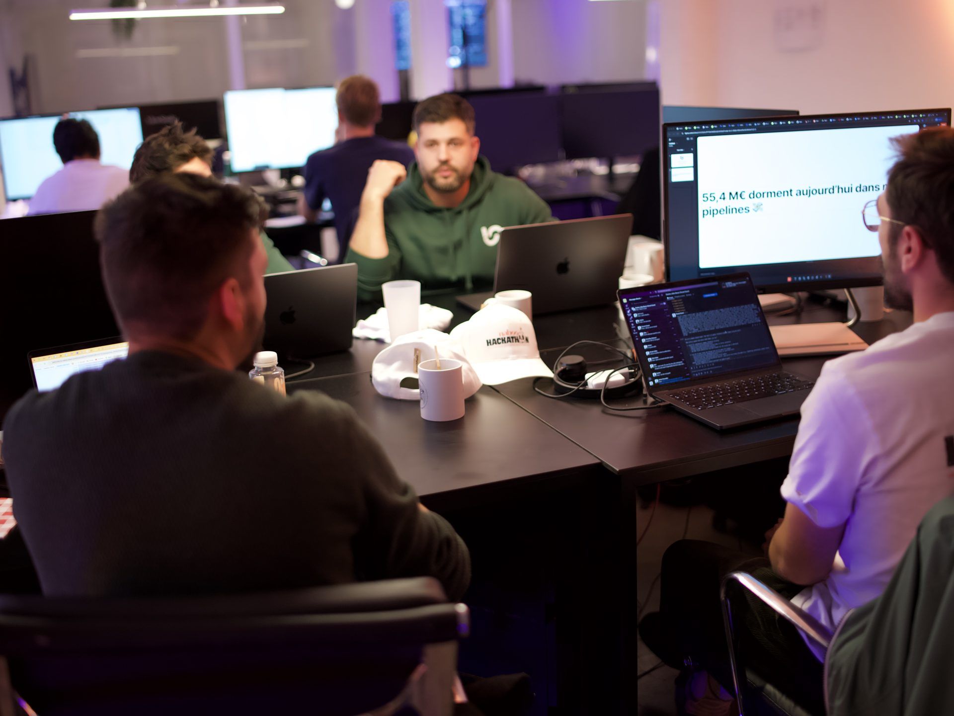 Developers and business colleagues working side by side at their desks during the Naboo hackathon