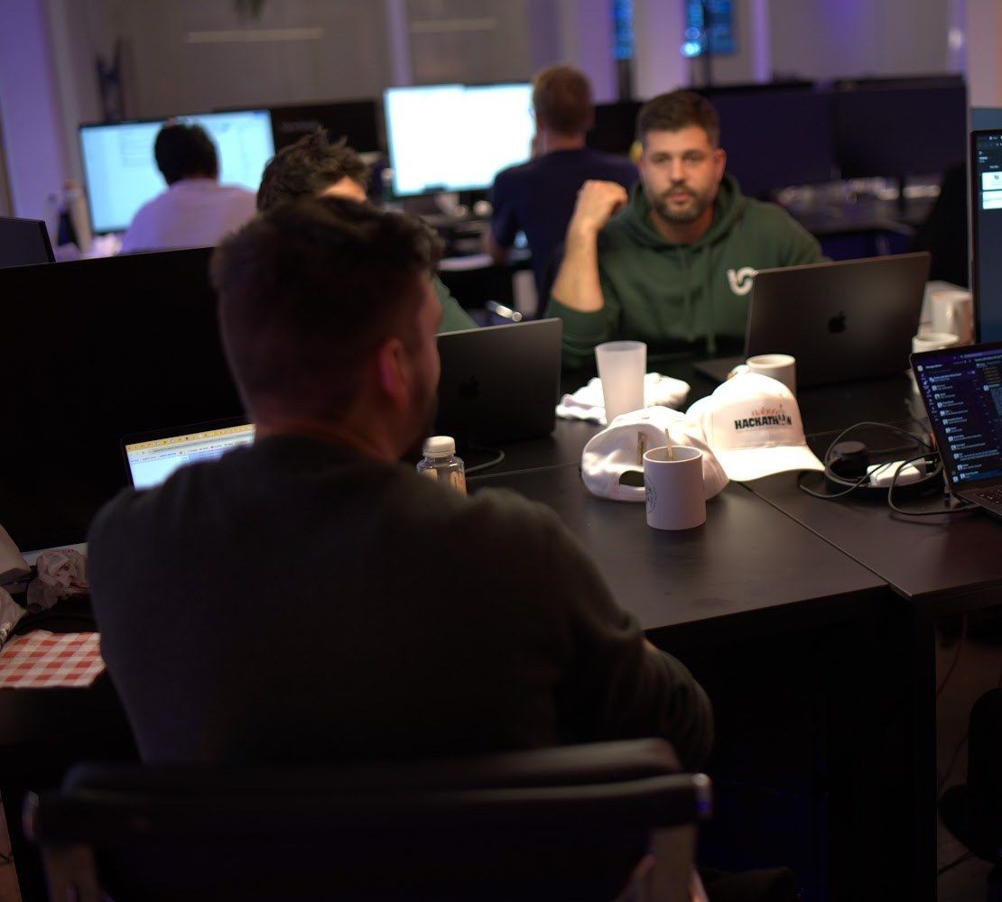 Small Naboo team working together at a shared table with laptops during the Naboo AI hackathon, Paris, October 2025