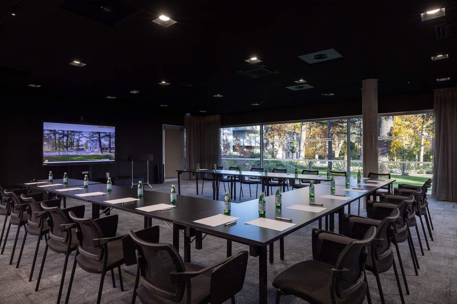 Modern corporate seminar room with U-shaped table setup, large screen